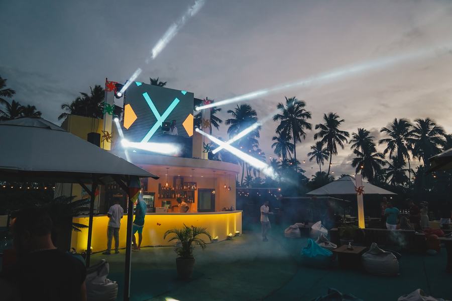 Estrutura com luzes cruzadas sobre bar à beira da piscina