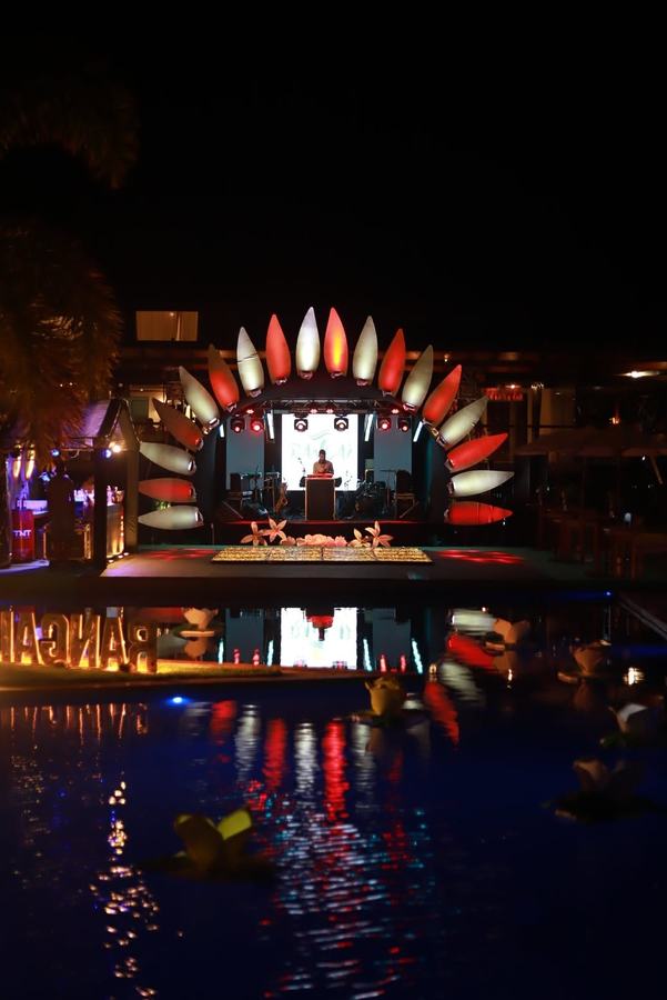 Arco decorativo à beira da piscina com DJ ao fundo